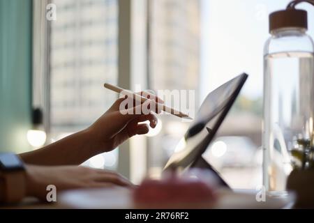 Grafikdesigner erstellt eine neue digitale Skizze mit einem Eingabestift. Freiberufliche Illustratorin, die in einem Café auf einem Tablet-Computer malt Stockfoto