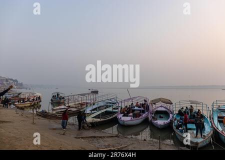 Varanasi: Bootsfahrt in Varanasi, Holzboote, die bei Sonnenaufgang am ganges-Ufer geparkt haben. Touristen benutzten Boote, um den Fluss zu überqueren und um sich die Stadt anzusehen. Stockfoto