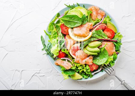 Frischer grüner Salat mit geräuchertem Lachs, Kirschtomaten, Feigen und Avocado auf weißem Tischhintergrund Stockfoto