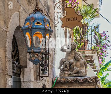 Werfen Sie einen Blick auf eine Gasse entlang der Hauptstraße der Touristenstadt Taormina. Kronleuchter aus stadttypischer lackierter Keramik. Taormina, Sizilien Stockfoto