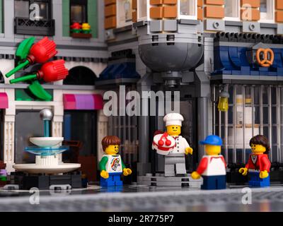 Tambov, Russische Föderation - 07. Januar 2023 Ein Lego-Konditormeister, der eine Torte vor der Haustür einer Bäckerei und herumstehende Kinder hat. Stockfoto