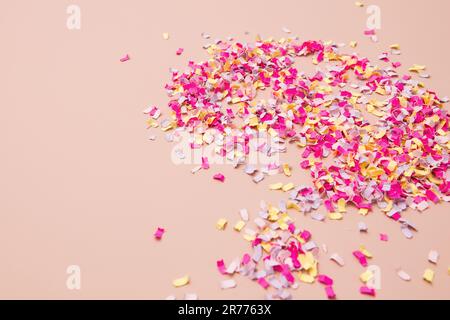 Leuchtend pinkfarbene, gelbe und farbenfrohe Streusel auf pinkfarbenem Hintergrund sorgen für eine feierliche Ankündigung. Stockfoto