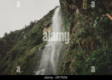 Ein Wasserfall, der die moosbedeckte Felsenklippe hinunterstürzt Stockfoto