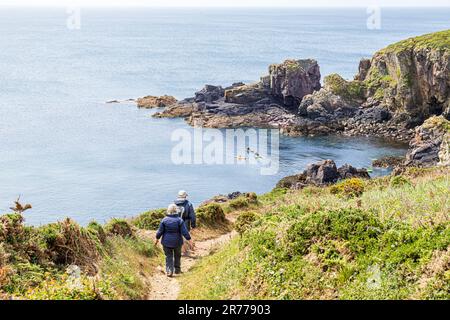 Spaziergänger auf dem Pembrokeshire Coast Path National Trail und Kanufahrer auf der St Non's Bay, der Halbinsel St. David im Pembrokeshire Coast National Park Stockfoto