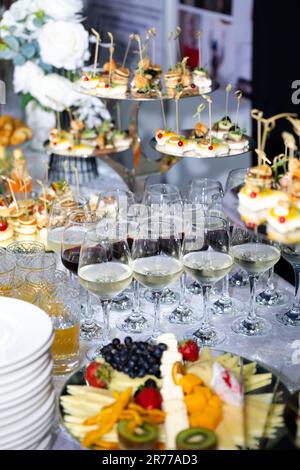 Gläser Weißwein und verschiedene Snacks am Büfetttisch der Veranstaltung. Stockfoto