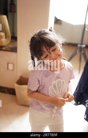 Unartige Kinderreaktion oder Gesichtsausdruck. Unartiges kleines Mädchen, das Süßigkeiten mit Gesichtsfarben isst. Stockfoto