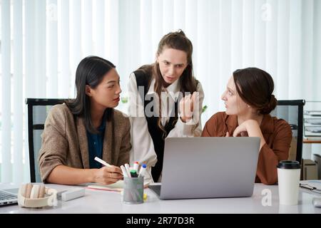 Gruppe von Geschäftskollegen, die während eines Meetings im Büro über ein Online-Projekt auf einem Laptop diskutieren Stockfoto