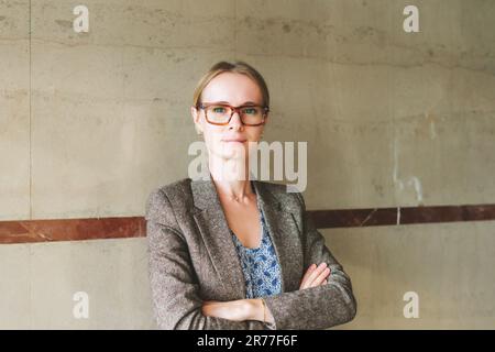 Porträt einer jungen 35-jährigen Frau mit brauner Brille und Jacke Stockfoto