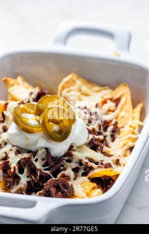 Nachos mit Rinderhackfleisch und Käse, serviert mit Schlagsahne und Jalapenos Stockfoto