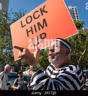 13. Juni 2023, Miami, Florida, USA: Gekleidet als Gefangener Anti-Trump-Demonstranten Kubanischer und Jersey City-Restaurantführer, DOMENIC SANTANA, verspottet die Profitrumpfer, zeigt mit dem Finger auf sie und schreit, während er ein Schild mit der Aufschrift hält: SPERRT IHN ein. In der Zwischenzeit waren wir früher in den USA Präsident Trump, der der erste Präsident ist, der sich einer Bundesanklage gegenübersieht, befindet sich im Bundesgerichtshof von Miami, wo er 37 Strafverfahren, einschließlich Spionage, ausgesetzt ist, die mit dem Umgang mit geheimen Dokumenten in seinem Anwesen in Florida Mar-a-Lago in Zusammenhang stehen. Trump hat sich in allen Anklagepunkten für nicht schuldig erklärt, hat in beiden Fällen jegliches Fehlverhalten abgestritten und hat Ehrenwort Stockfoto