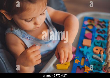 Kindermädchen, das mit pädagogischem Spielzeug in der Kindertagesstätte spielt. Spielzeug aus Holz für Kinder. Kleinkinder lernen Zahlen. Stockfoto