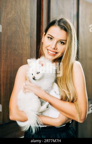 Außenporträt einer glücklichen jungen Frau mit dem weißen pommern-spitz-Welpen Stockfoto