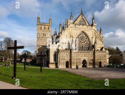 Sonne scheint auf der kunstvoll verzierten gotischen Westwand und dem Normannen Nordturm der Exeter Cathedral in Devon. Stockfoto