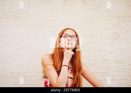 Porträt eines niedlichen, 10-11-Jährigen jungen Mädchens mit langen roten Haaren und Brille Stockfoto