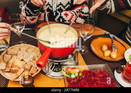 Freunde essen Käsefondue in einem gemütlichen, traditionellen schweizer Restaurant Stockfoto