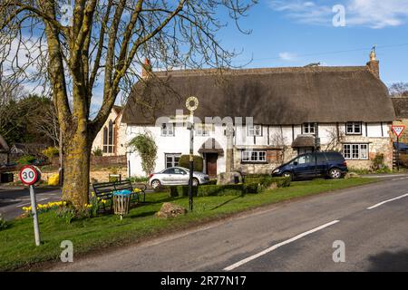 Traditionelle strohgedeckte Hütten stehen neben dem Dorfgrün in Ashbury in Oxfordshires Tal des weißen Pferdes. Stockfoto