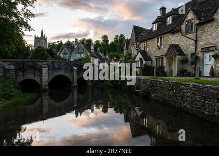 Die Sonne geht über den malerischen Cotswold Steinhäusern und der Brückenbrücke des Dorfes Castle Combe in Wiltshire unter. Stockfoto
