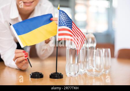 Bürokoordinator setzt Flaggen der Ukraine und der Vereinigten Staaten auf den Tisch Stockfoto