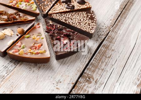 Kreative Zusammensetzung Schokolade in Form einer Pizza mit kandierten Früchten, Nüssen, trockenen Beeren, Schokoladen-Pizza und Zutaten auf Holzhintergrund. Stockfoto