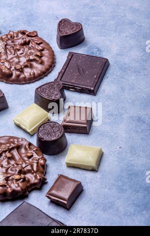 Verschiedene Schokoladenprodukte, die im Studio auf hellgrauem Hintergrund mit weißer Textur fotografiert wurden. Dunkle Schokolade, Milchschokolade, weiße Schokolade, C. Stockfoto