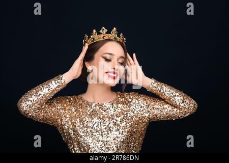 Wunderschöne junge Frau mit luxuriöser Krone auf schwarzem Hintergrund Stockfoto