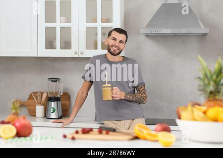 Hübscher Mann mit leckerem Smoothie in der Küche Stockfoto