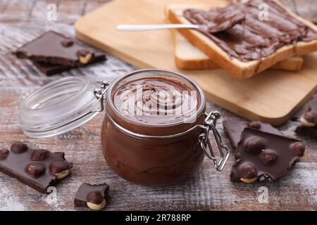 Becher mit leckerer Paste und Schokoladenstückchen auf einem Holztisch Stockfoto