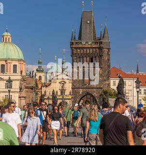 PRAG, TSCHECHISCHE REPUBLIK - Touristen, die die Karlsbrücke überqueren. Der Old Town Bridge Tower befindet sich hinter dem Gebäude. Stockfoto