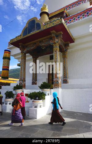 Buddhistische Anhänger, die Gebetsperlen tragen, sprechen Gebete auf, während sie durch das National Memorial Chorten (Stupa) in Thimphu, Bhutan, spazieren. Stockfoto