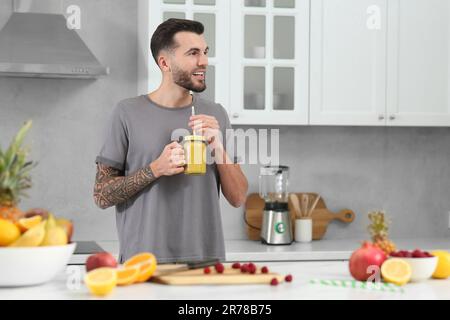 Hübscher Mann mit leckerem Smoothie in der Küche. Platz für Text Stockfoto