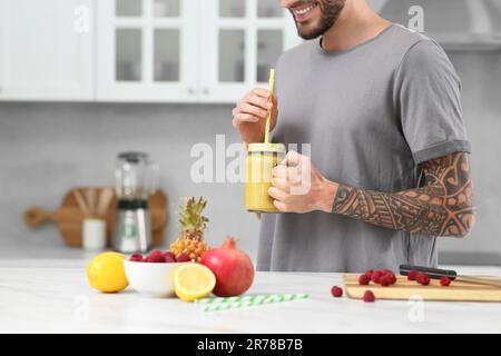 Mann mit leckerem Smoothie in der Küche, Nahaufnahme. Platz für Text Stockfoto