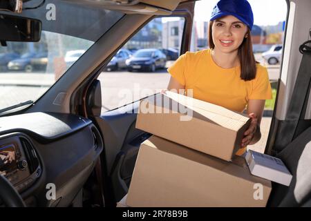 Der Kurier nimmt das Paket vom Auto ab. Lieferservice Stockfoto