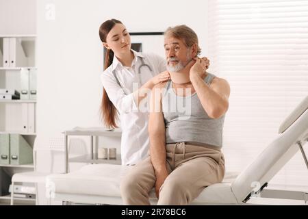 Orthopädin, der das Halsband am Hals des Patienten in der Klinik anlegt Stockfoto