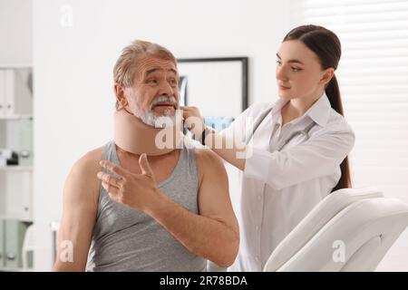 Orthopädin, der das Halsband am Hals des Patienten in der Klinik anlegt Stockfoto