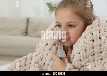 Kleines Mädchen mit Vernebler zur Inhalation zu Hause Stockfoto