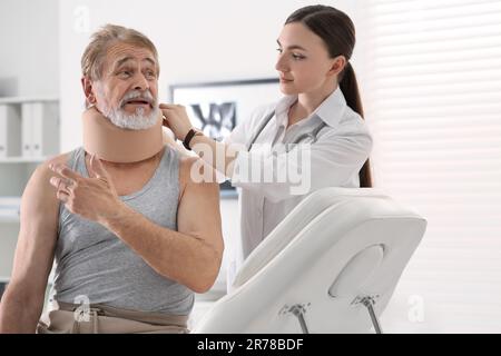 Orthopädin, der das Halsband am Hals des Patienten in der Klinik anlegt Stockfoto