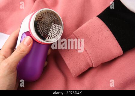 Frau, die den Rasierer in der Nähe des Pullis mit Fusseln hält, Nahaufnahme Stockfoto