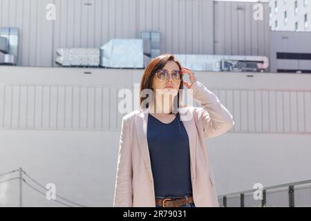 Portrait Confidence Mature 40 yo Business Woman, Manager. Industriebau, Fabrik im Hintergrund. Weiße Burnette Mit Sonnenbrille Stockfoto