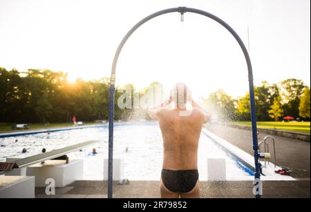Hannover, Deutschland. 14. Juni 2023. Ein frühmorgendlicher Schwimmer steht unter der Dusche im Licht der aufgehenden Sonne am Annabad Outdoor Pool. Kredit: Julian Stratenschulte/dpa/Alamy Live News Stockfoto