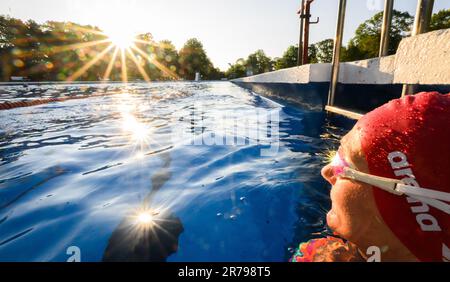 Hannover, Deutschland. 14. Juni 2023. Die aufgehende Sonne spiegelt sich in der Schwimmbrille eines frühmorgendlichen Schwimmers am Annabad Outdoor Pool wider. Kredit: Julian Stratenschulte/dpa/Alamy Live News Stockfoto