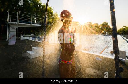 Hannover, Deutschland. 14. Juni 2023. Ein frühmorgendlicher Schwimmer steht unter der Dusche im Licht der aufgehenden Sonne am Annabad Outdoor Pool. Kredit: Julian Stratenschulte/dpa/Alamy Live News Stockfoto