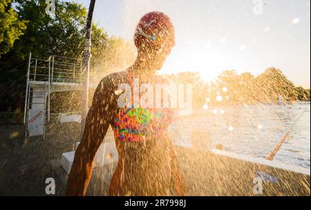 Hannover, Deutschland. 14. Juni 2023. Ein frühmorgendlicher Schwimmer steht unter der Dusche im Licht der aufgehenden Sonne am Annabad Outdoor Pool. Kredit: Julian Stratenschulte/dpa/Alamy Live News Stockfoto