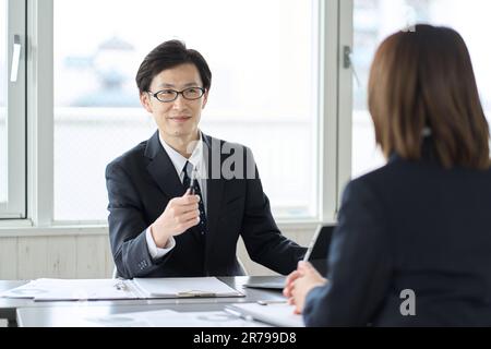 Asiatischer Geschäftsmann, der seinen Untergebenen lobt Stockfoto