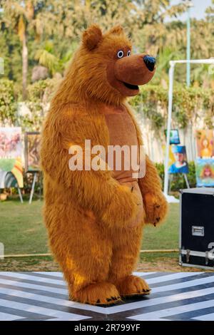 Großer brauner Teddybär im Garten, großes braunes Bärenkostüm von Kinderparty-Entertainer, spielbereit mit Kindern, alles gute zum Geburtstag des Kindes mit Chili Stockfoto