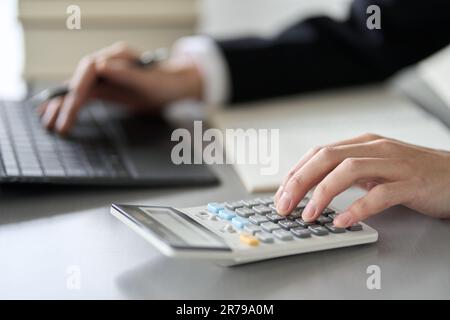 Die Hand eines männlichen Steuerbuchhalters, der mit einem Taschenrechner rechnet Stockfoto