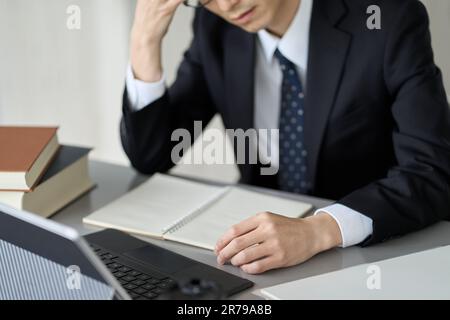 Besorgter asiatischer Geschäftsmann, der seinen Kopf hält Stockfoto