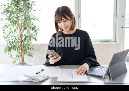 Asiatische Frau, die Steuererklärungen auf dem Smartphone einreicht Stockfoto