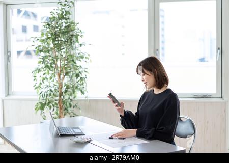 Asiatische Frau, die Steuererklärungen auf dem Smartphone einreicht Stockfoto