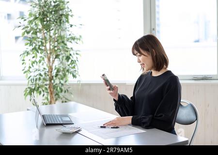 Asiatische Frau, die Steuererklärungen auf dem Smartphone einreicht Stockfoto