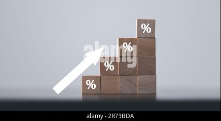 Holzwürfel mit Prozentsymbol, Prozentpfeilen und aufwärts steigenden Pfeilen auf Holzwürfeln schließen. Die Zinssätze für Hypothekarkredite steigen oder der Preis steigt Stockfoto